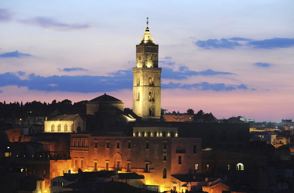 Verlichte kathedraal met hoge toren bij zonsondergang in Puglia, Italië.