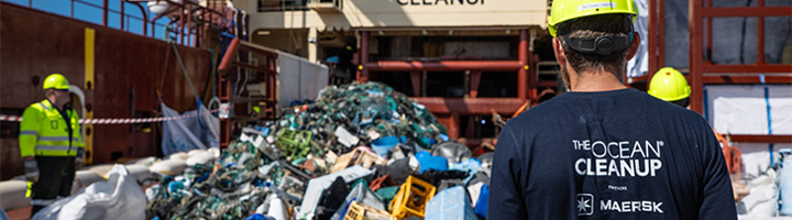 The Ocean Cleanup-team bij een grote berg ingezameld plastic op een schip.