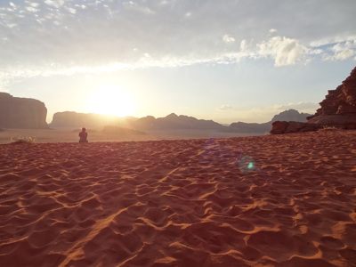 Zonsondergang in de Wadi Rum-woestijn met zandduinen en rotsformaties tijdens route Jordanië en Israël.