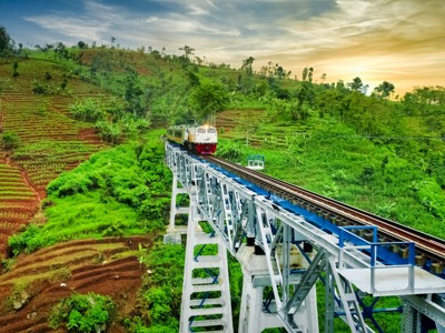Trein op een spoorbrug door groene rijstterrassen op Java, tijdens de route Java en Bali.