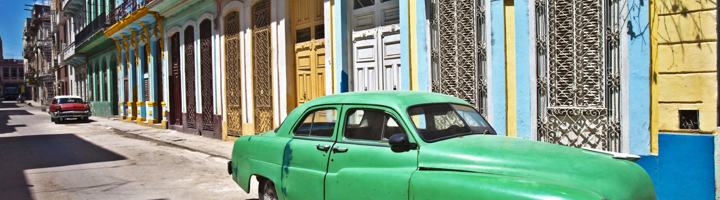 Groene klassieke auto in een kleurrijke straat in Havana, Cuba.