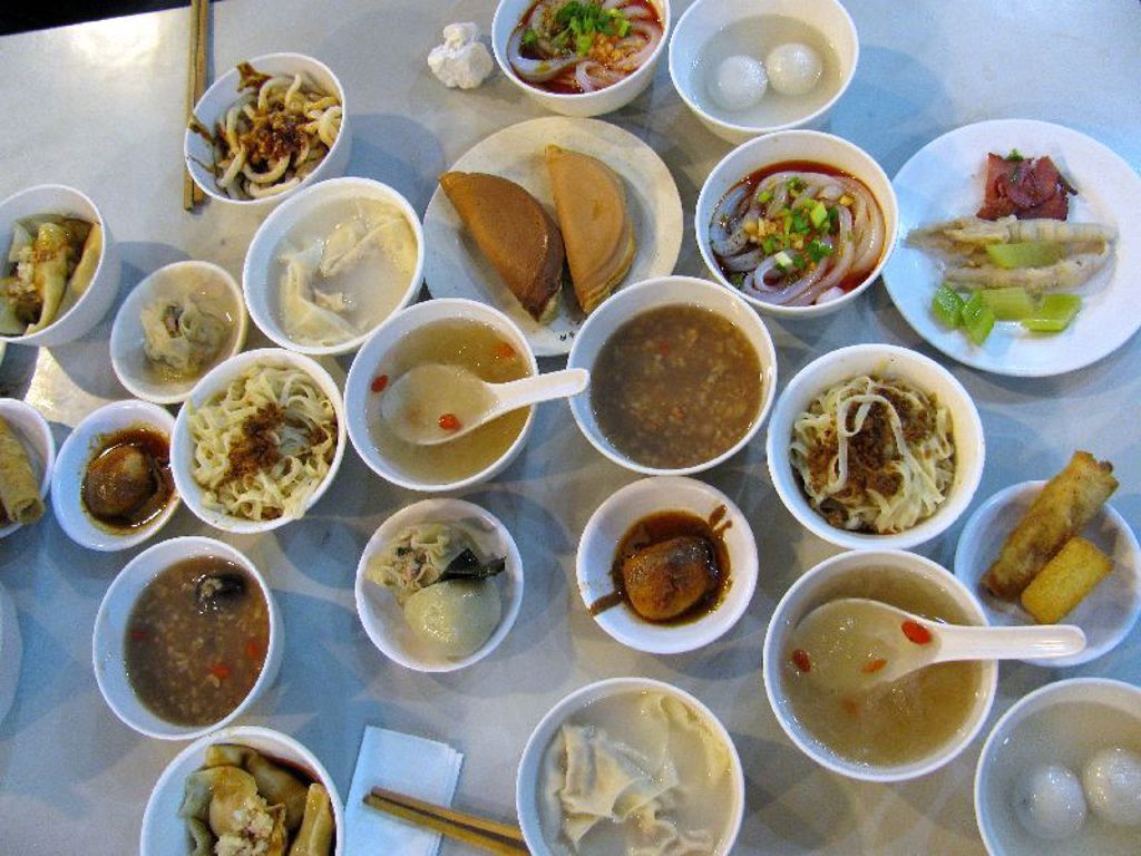 Chinese maaltijd met diverse dim sum, noedelsoep en dumplings op tafel tijdens Familiereis China.