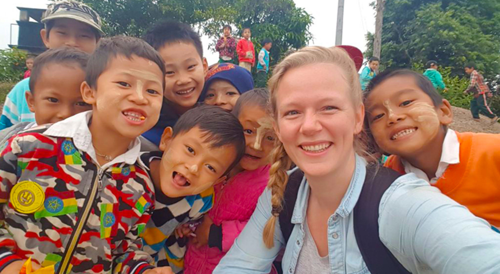 selfie met kinderen en locals in myanmar Reiziger maakt een vrolijke selfie met een groep kinderen met thanaka op hun gezicht.