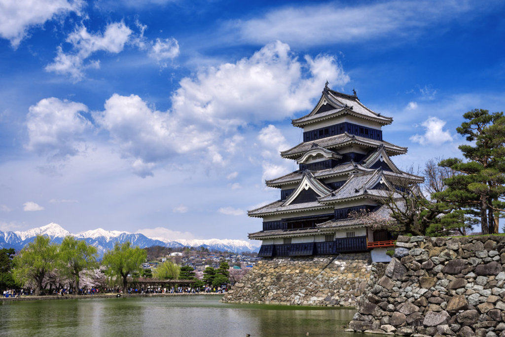 Matsumoto-jo kasteel in Japan met gracht en bergen op de achtergrond, hoogtepunt van een groepsrondreis Japan.