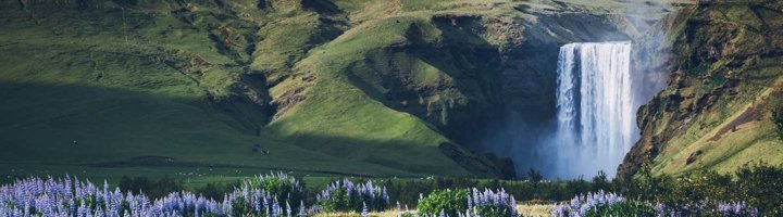 Skogafoss-waterval in IJsland, met een brede watergordijn en mist boven de rotsen.