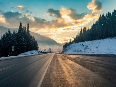 Sneeuwlandschap langs de Route Canada met bergweg door naaldbos bij zonsopkomst.