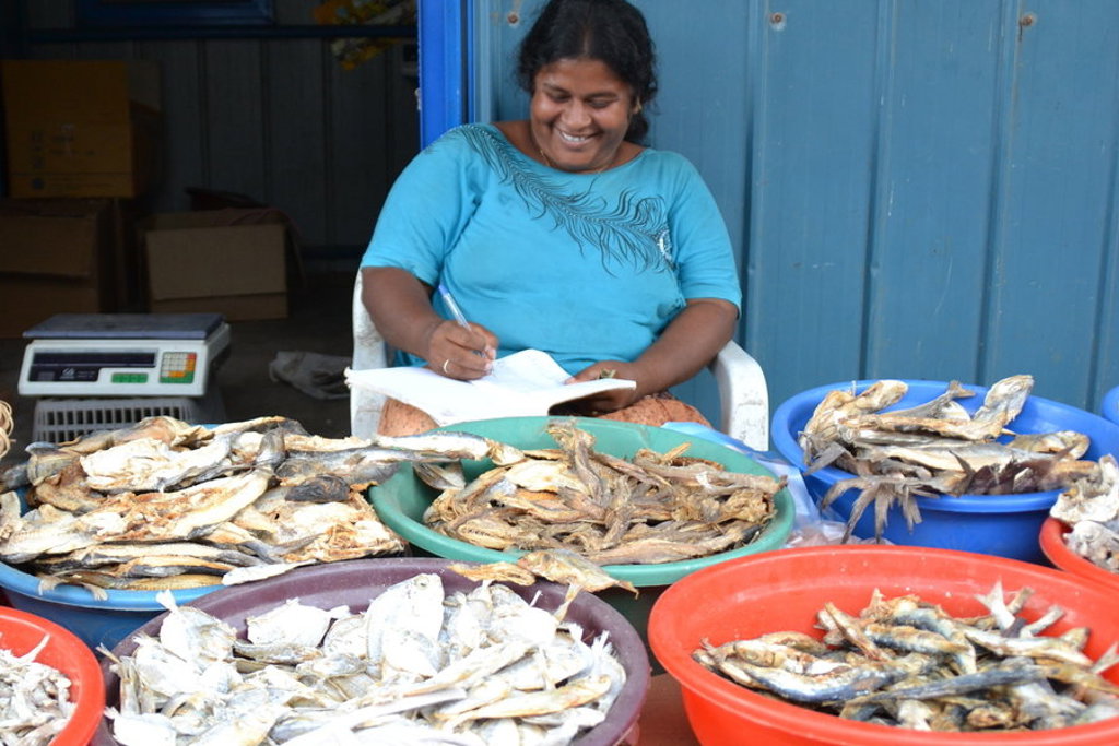 Vrouw noteert bestellingen bij kraam met gedroogde vis op een markt in Sri Lanka tijdens groepsrondreis Hoogtepunten.