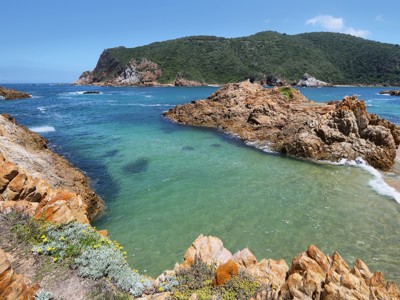 Rotsachtige kust en turkooisblauwe baai langs de Zuid-Afrikaanse Tuinroute.