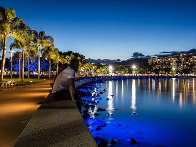 Avondwandeling langs de Esplanade in Cairns met palmbomen en lichtreflecties in de baai.
