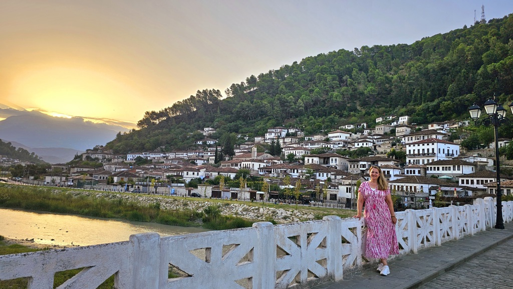 Uitzicht op het historische stadje Berat in Albanië bij zonsondergang, met witte huizen tegen een groene heuvel.