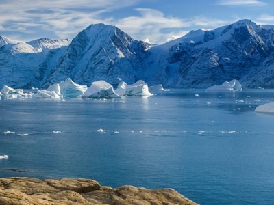 Besneeuwde bergen en drijvende ijsbergen in een Arctische fjord bij Groenland en Spitsbergen.