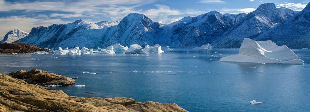 Besneeuwde bergen en drijvende ijsbergen in een Arctische fjord bij Groenland en Spitsbergen.