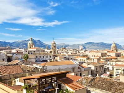 Uitzicht over de daken en kathedralen van Palermo op Sicilië, met bergen op de achtergrond.