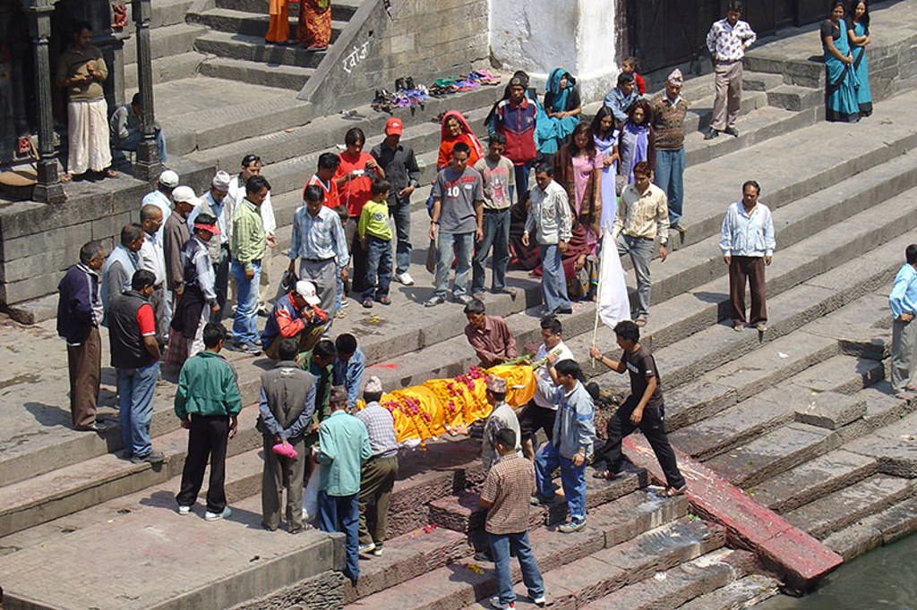 Mensen verzamelen zich op de trappen van een rivierghat in Noord-India tijdens een ceremonie.