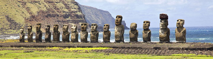 Moai-beelden op Paaseiland langs de kust, met oceaan en kliffen op de achtergrond.