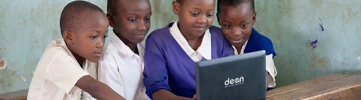Leerlingen gebruiken samen een laptop in de klas, passend bij onderwijsprojecten in Kenia en Bolivia.