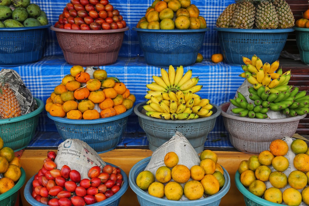 Fruitkram op Bali met manden vol bananen, sinaasappels en ananas op een lokale markt.