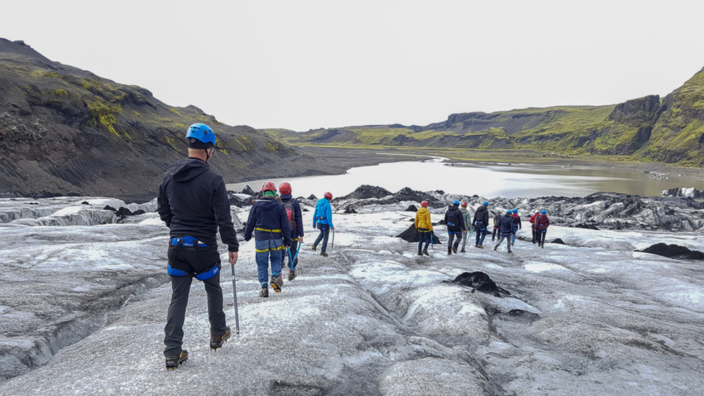 Groep wandelt met helm en stijgijzers over een gletsjer tijdens een 22-35ers reis in IJsland.