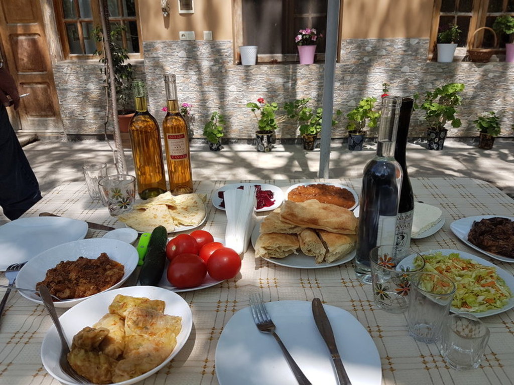 Georgische lunch met vers brood, salades en lokale wijn op een gedekte tafel tijdens een groepsrondreis door Georgië.