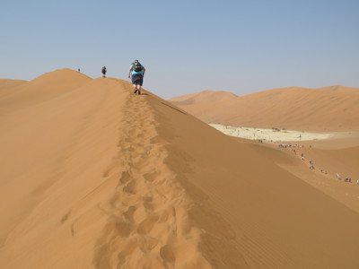Wandelaars op hoge zandduin in de Namibwoestijn tijdens de route Victoria Falls - Windhoek.