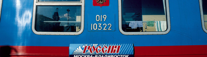 Blauwe Trans-Siberië-treinwagon met ramen en routebord Moskou–Vladivostok.