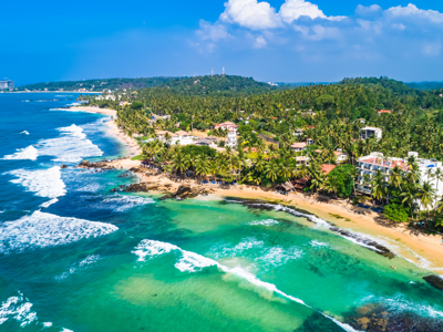 de palmstrandkust in Sri Lanka met turquoise zee en golven langs het zandstrand.