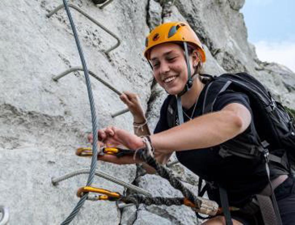 Tiener klimt via een gezekerde klettersteigwand in de Pyreneeën bij Canigou, Frankrijk.