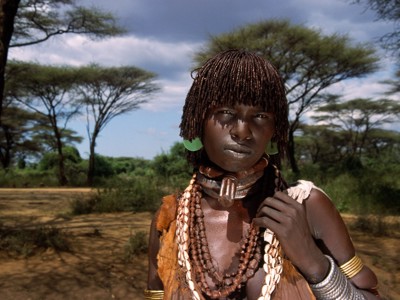 Portret van een vrouw met kralenkettingen en oorbellen in het landschap van Zuid-Ethiopië.