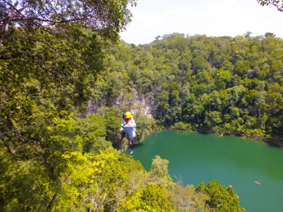 Ziplinen boven een turquoise cenote in de jungle van Mexico.