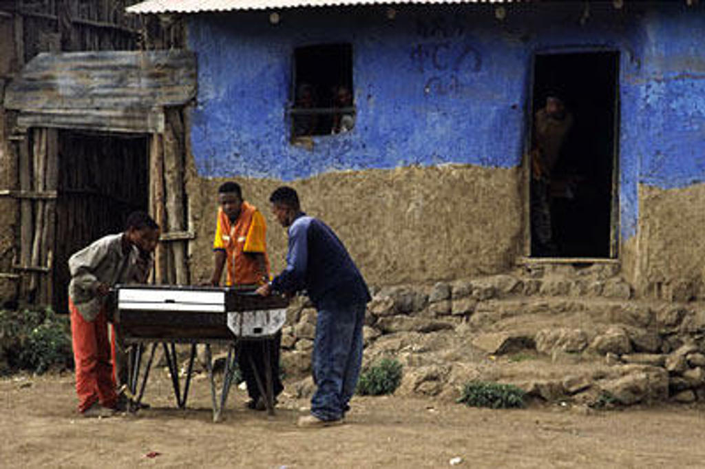Mannen spelen tafelvoetbal voor een blauw huis in Ethiopië tijdens een groepsrondreis.