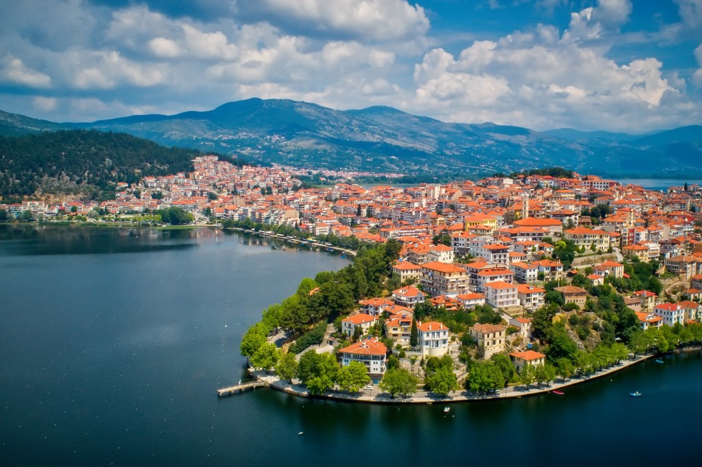 Uitzicht op Kastoria met roodkleurige daken aan het Orestiada-meer, Noord-Griekenland, met bergen op de achtergrond.
