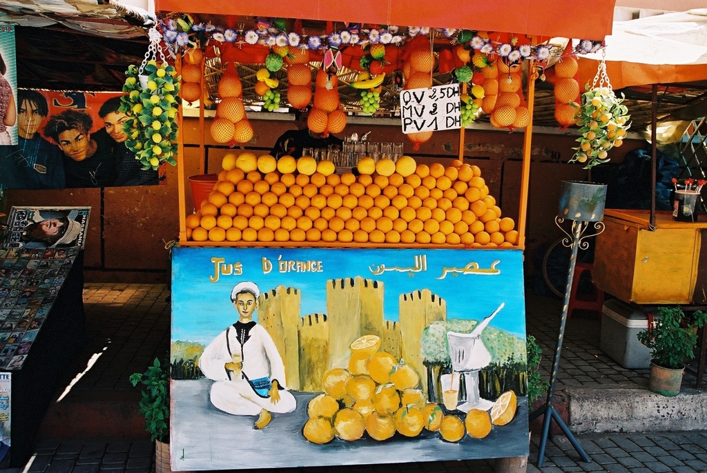 Marktkraam met stapels sinaasappels en vers sinaasappelsap in Marokko tijdens Familiereis Marokko Zomer.