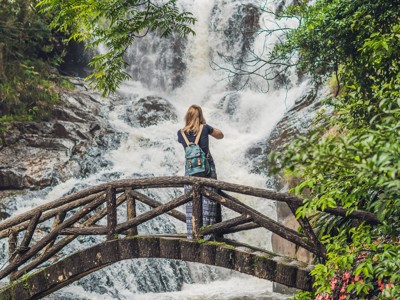 Reiziger op houten brug bij waterval in Vietnam tijdens de Route Vietnam.