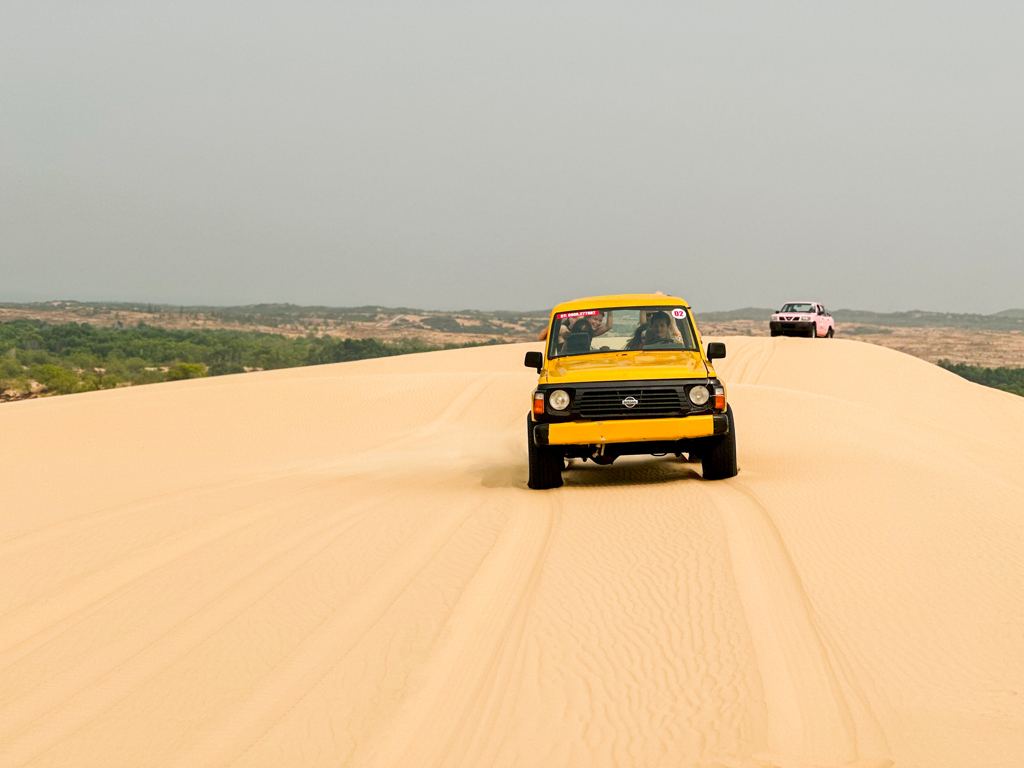 Gele jeep rijdt over zandduinen tijdens 22-35ers reis Vietnam.
