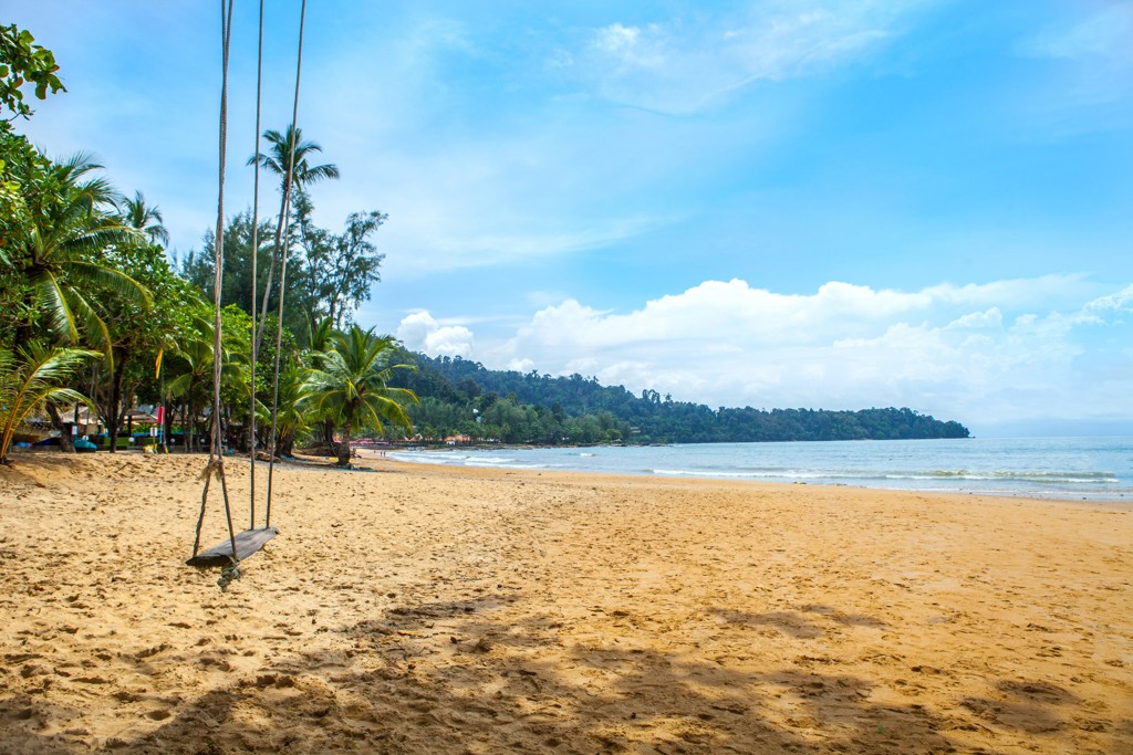 Rustig zandstrand in Thailand met palmbomen, zee en schommel aan touwen, tijdens Familiereis Thailand Comfort-Plus.