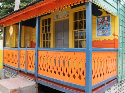 Kleurrijk Jamaicaans houten huis met veranda en houtsnijwerk, langs de Route Jamaica 16 dagen.