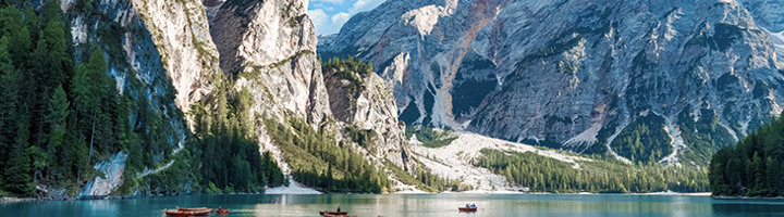 Turquoise bergmeer met roeiboten tussen hoge Alpenpieken, onderdeel van reisroutes dwars door Europa.