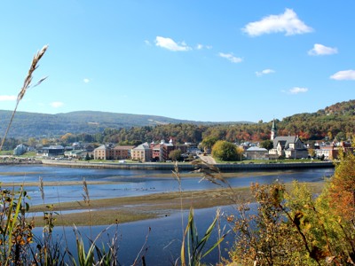 Uitzicht op Baie-Saint-Paul aan de rivier in Oost-Canada, met kerk en heuvels in herfstkleuren.