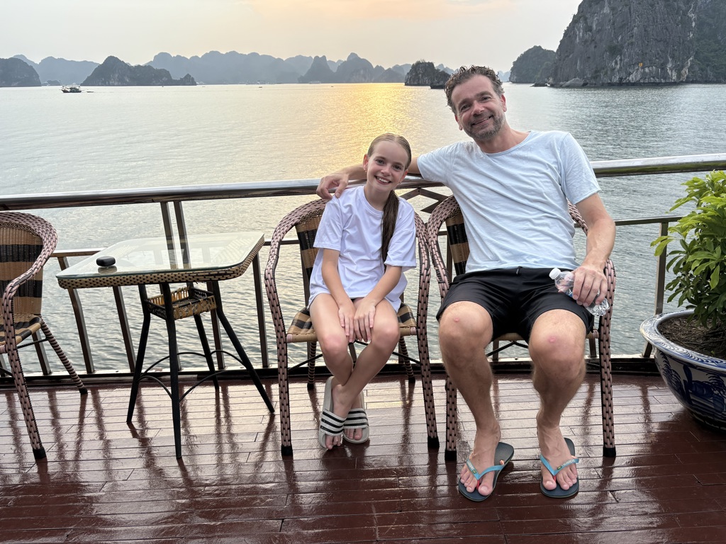Vader en dochter op het dek van een boot in Ha Long Bay tijdens een familiereis Vietnam.