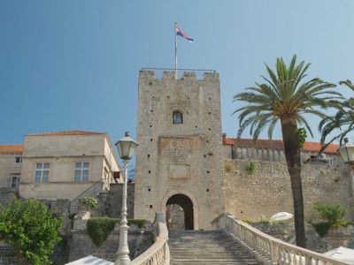 Stadspoort en vestingmuur met palmbomen in Korčula, Kroatië, op de route Kroatië en Montenegro.