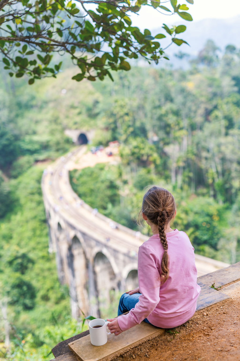 Meisje kijkt uit over de Nine Arches Bridge in Sri Lanka tijdens een familiereis.