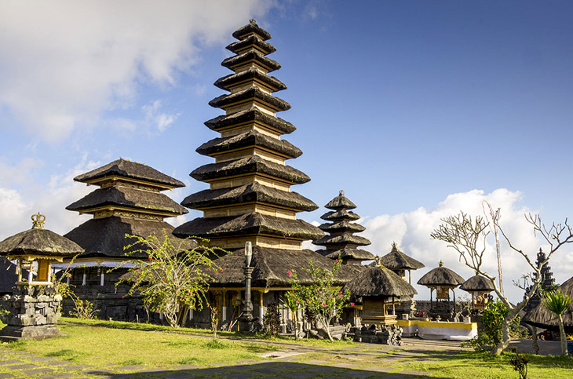 Tempel op Bali Balinese tempelcomplex met meerlaagse pagode en rieten daken onder een blauwe lucht.