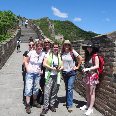 Groepsrondreis China: reizigers op de Chinese Muur met groen berglandschap en blauwe lucht.