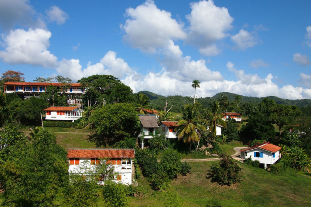 Groene heuvels met palmbomen en kleurrijke huizen op het Cubaanse platteland tijdens een groepsrondreis Cuba.
