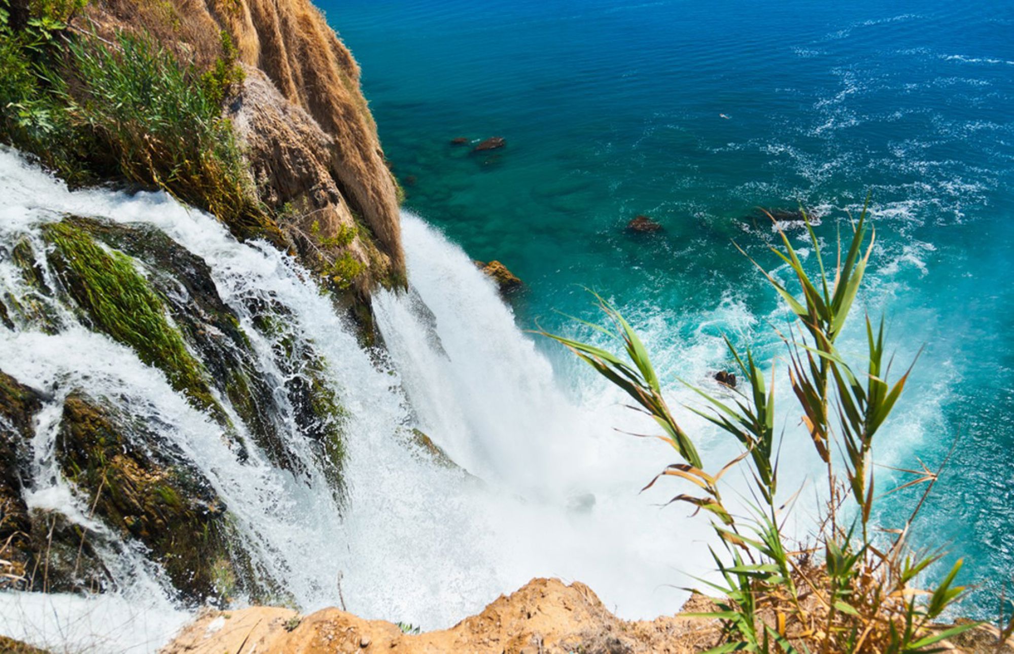 Waterval die van een rotswand in de turquoise zee stroomt aan de kust van Turkije.