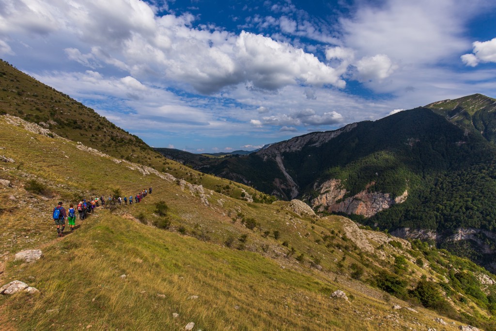 Wandelaars in groep op bergpad met uitzicht op groene vallei en rotswanden in Bosnië en Herzegovina.