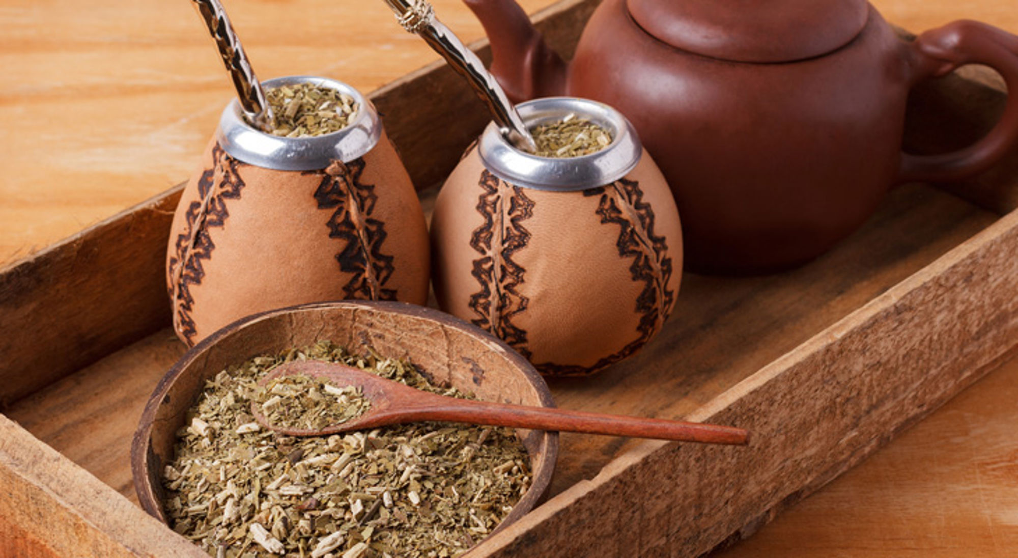 Mate drinken in Buenos Aires Kalebassen met yerba mate en rietjes op een houten dienblad, met theepot en losse kruiden.