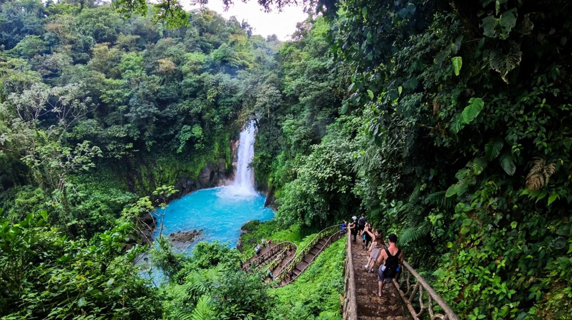 Waterval met turquoise lagune en wandelpad door het regenwoud in Costa Rica.