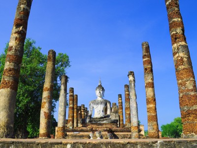 Zittend Boeddhabeeld tussen oude zuilen in Sukhothai, Thailand.