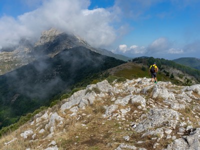 Wandelaar op rotsige bergkam met wolken rond de toppen tijdens de route Amalfikust.